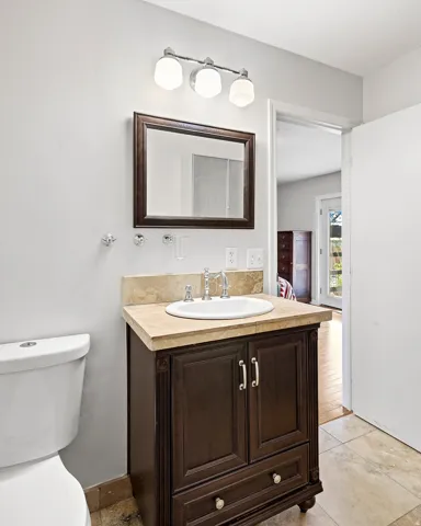 Dark wood-finish vanity with a light-toned countertop, undermount sink, and chrome fixtures