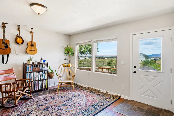 Hardwood-finish flooring, tile entry, two large windows, white exterior door with glass insert, and a flush-mount ceiling light