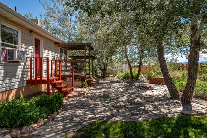 Stone patio with a designated fire pit area, surrounded by mature trees