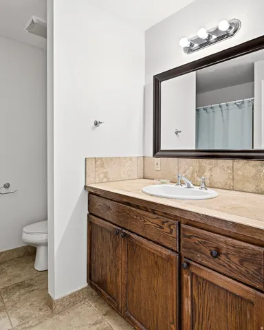 Wood-finish vanity with an integrated sink, tile countertop, and a framed mirror