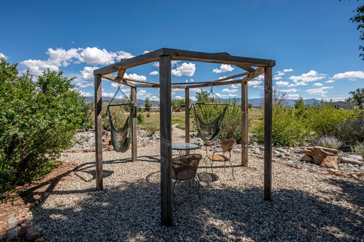 Wood pergola structure with a gravel ground cover and surrounding landscaping