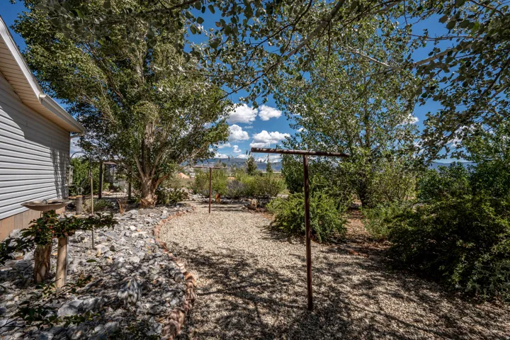 Landscaped grounds featuring mature trees, a gravel pathway, and a rock garden