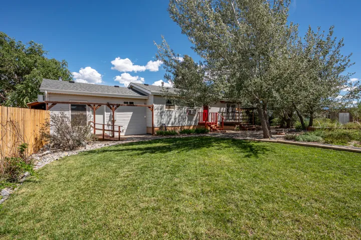 Expansive grassy lawn with a privacy fence and mature trees