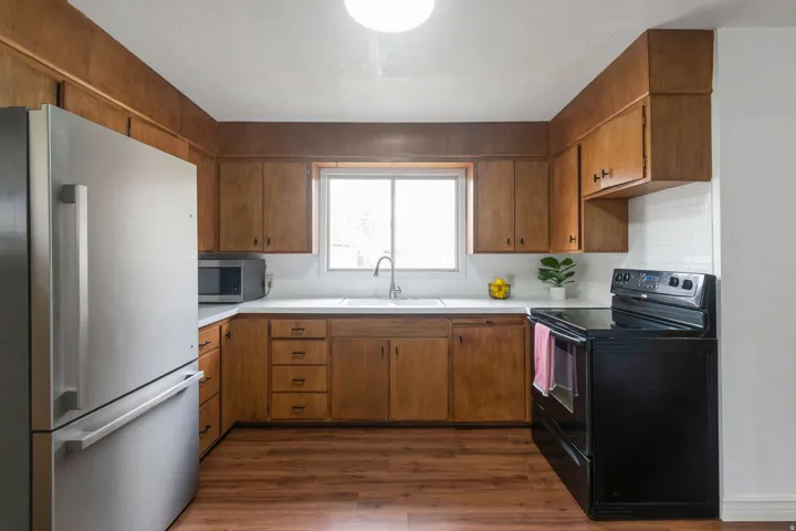 Kitchen featuring wood-finish cabinetry, white countertops, a white subway tile backsplash, and wood-finish flooring