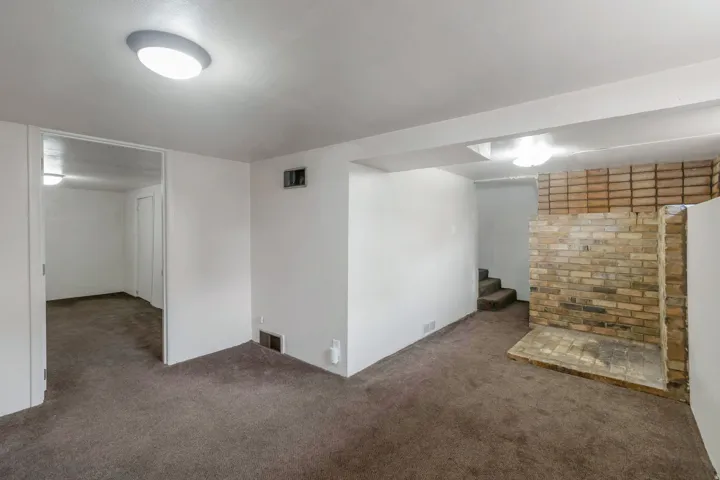 Finished interior space with wall-to-wall carpeting and a brick-finish fireplace