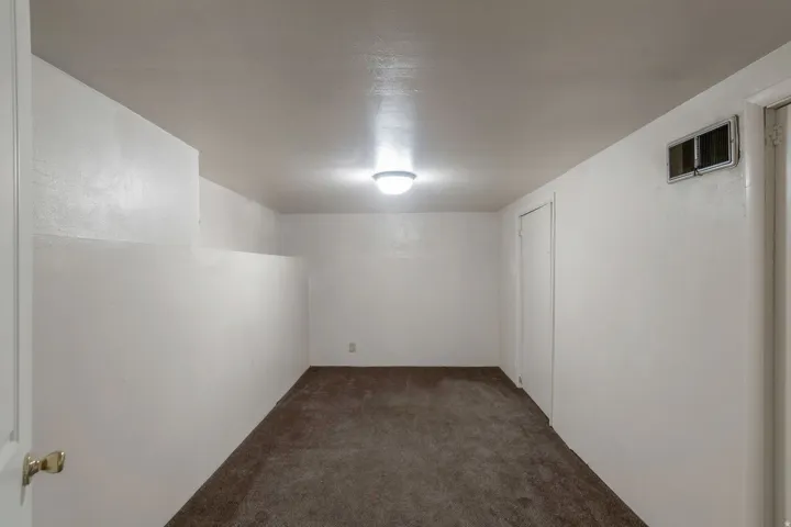 Wall-to-wall carpeting, flush-mount ceiling light, white painted walls, and a white interior door