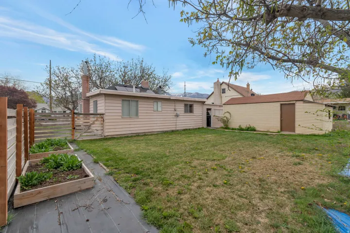 Expansive grassy yard with raised garden beds and a wood fence