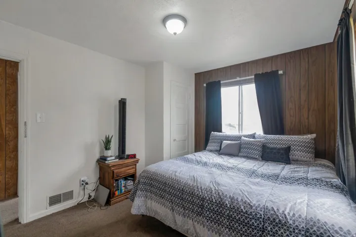 Paneled accent wall, window with natural light, recessed ceiling light, carpeted flooring, and a white interior door