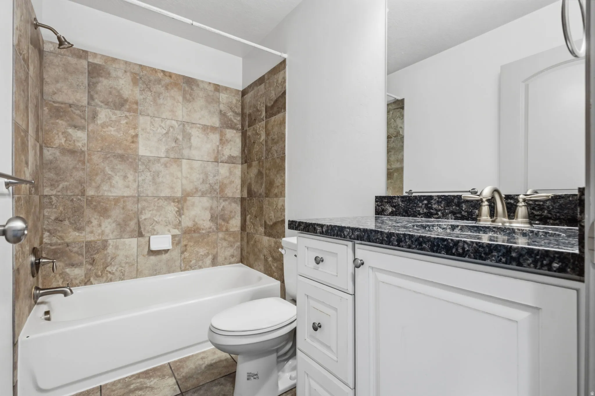 White vanity with dark stone countertop, undermount sink, and brushed nickel faucet