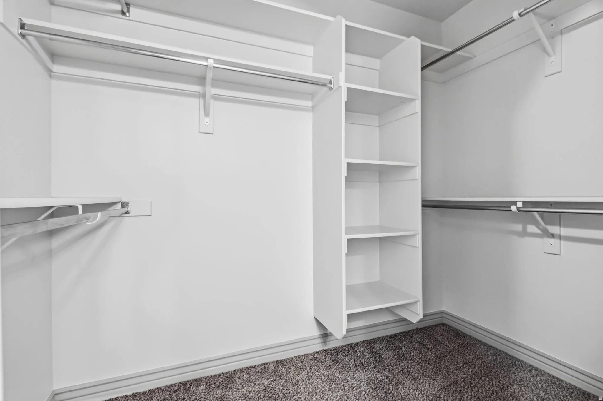 Built-in shelving, multiple hanging rods, and carpet flooring