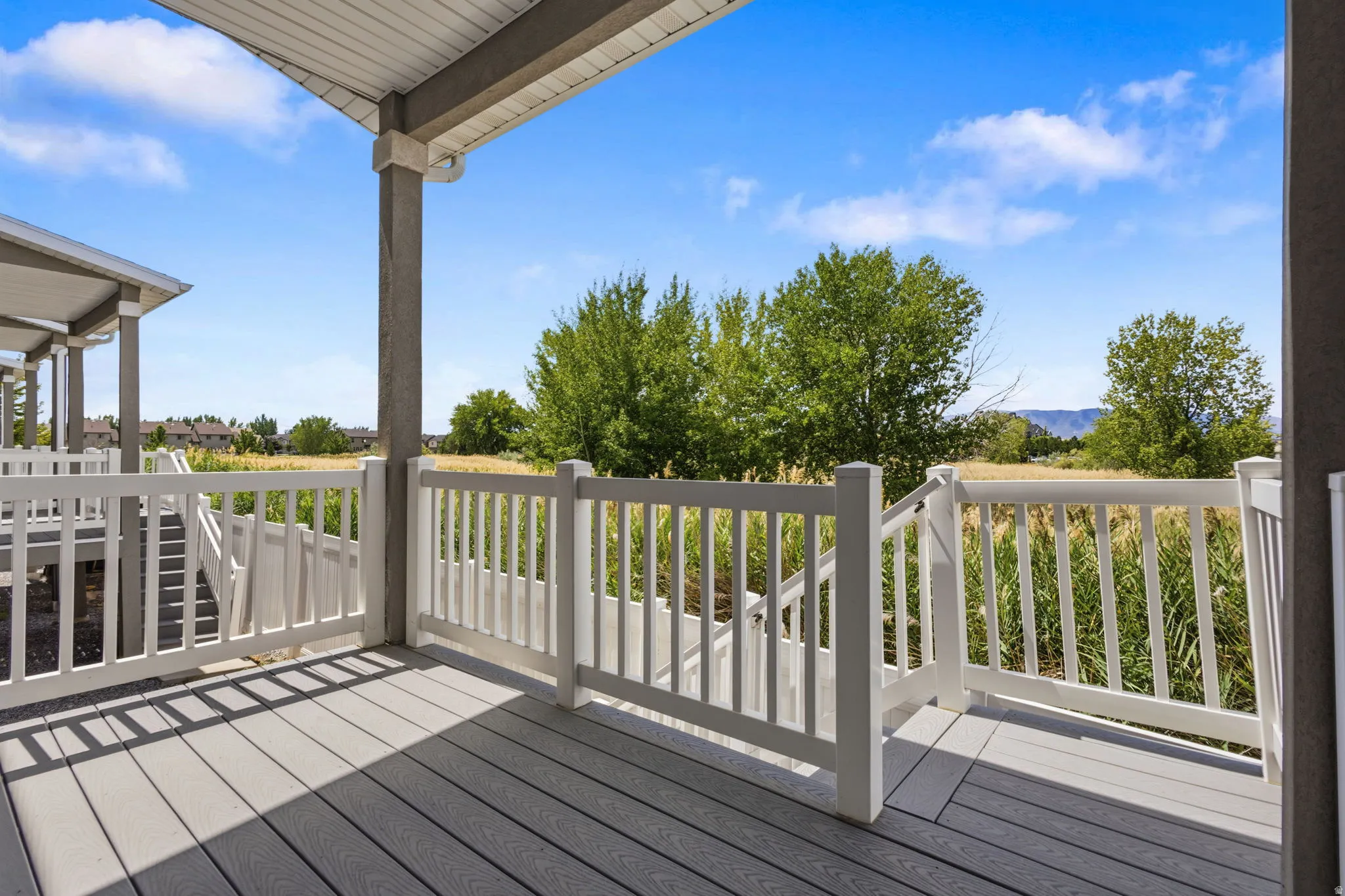 Covered outdoor deck with composite decking, white railing, and exterior columns