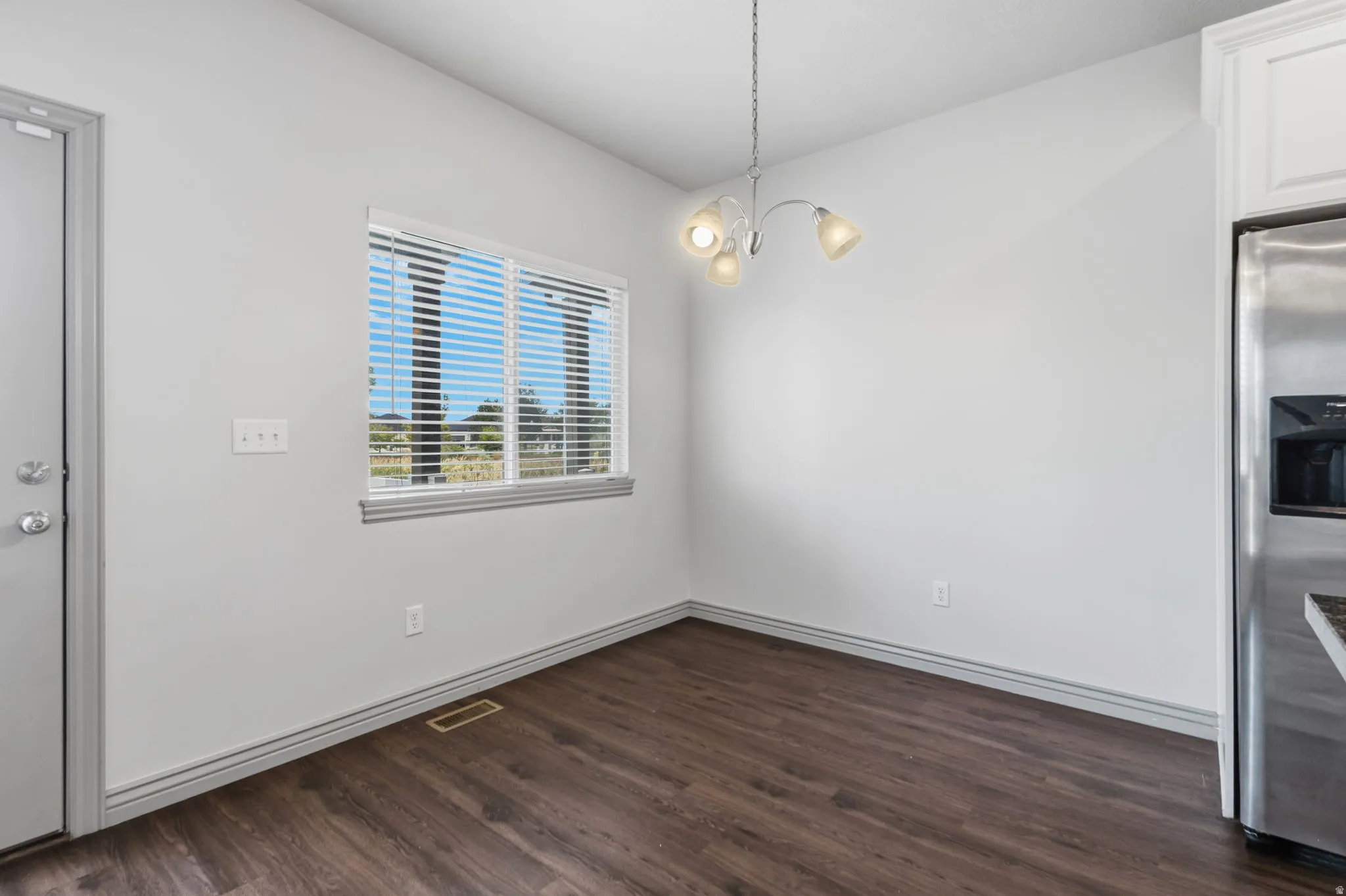 Wood-finish flooring, white walls, and a window with blinds