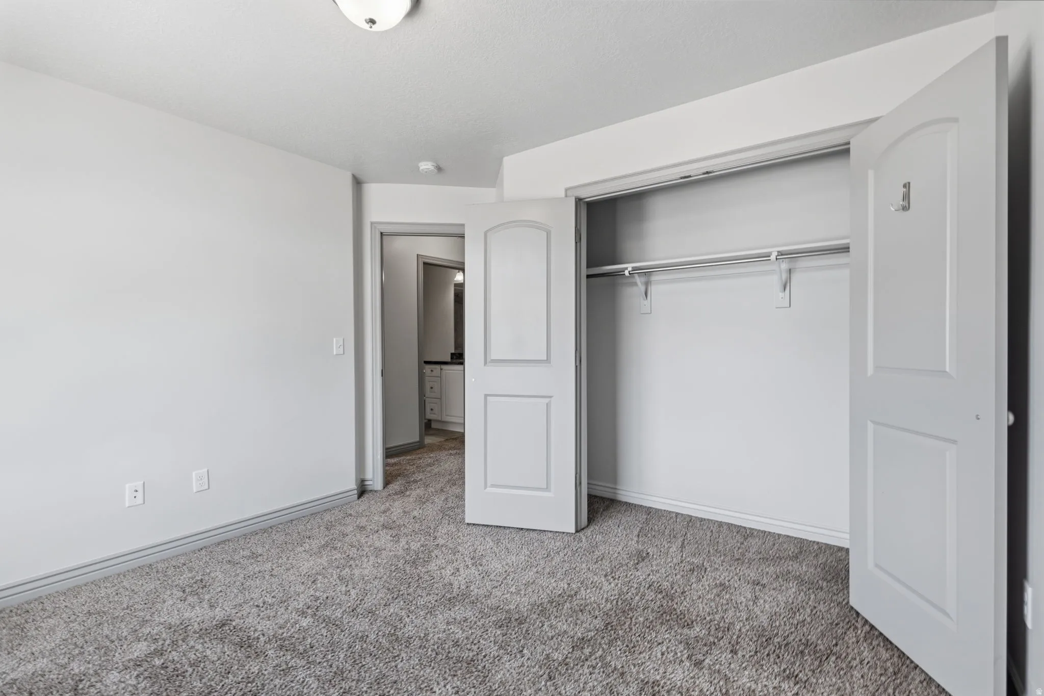 Plush carpeting, bi-fold closet doors, built-in closet shelving, and a semi-flush mount ceiling light fixture