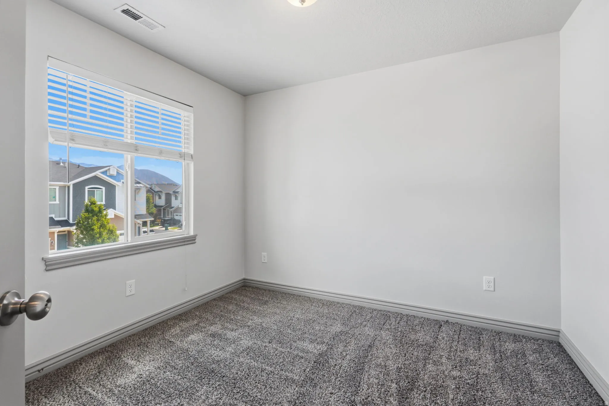 Neutral wall paint, carpet flooring, window with blinds, and white trim
