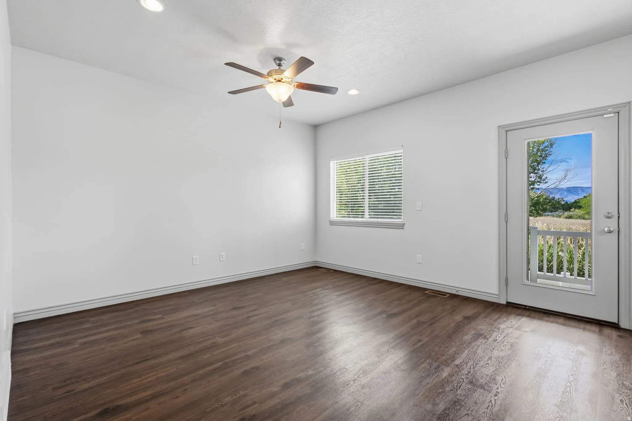 Spacious room featuring wood-finish flooring and a ceiling fan