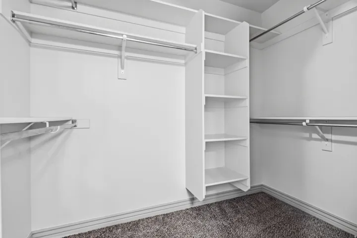 Built-in shelving, multiple hanging rods, and carpet flooring
