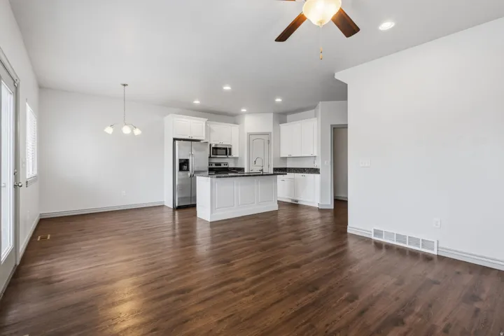 Wood-finish flooring, white cabinetry, stainless steel appliances, recessed lighting, and a ceiling fan