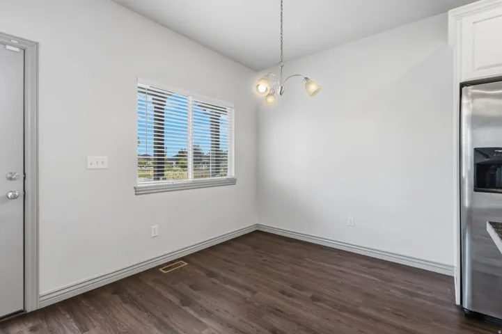 Wood-finish flooring, white walls, and a window with blinds