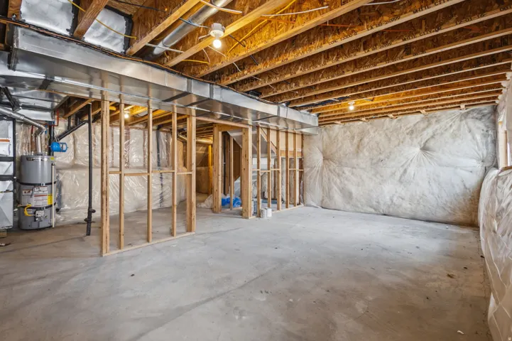 Unfinished basement with concrete flooring, exposed wood joists, and framed interior walls