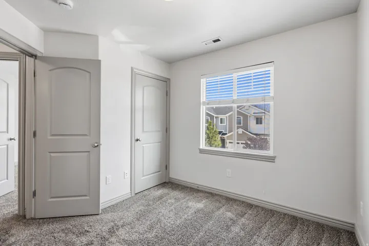 Recessed lighting, gray carpeting, a single window with blinds, and multiple interior doors with arch paneling