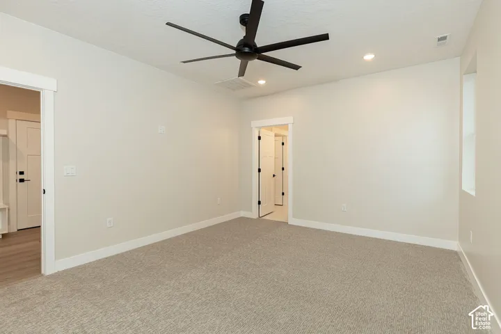 Spacious room with neutral-toned carpet, recessed lighting, a ceiling fan, and a single window