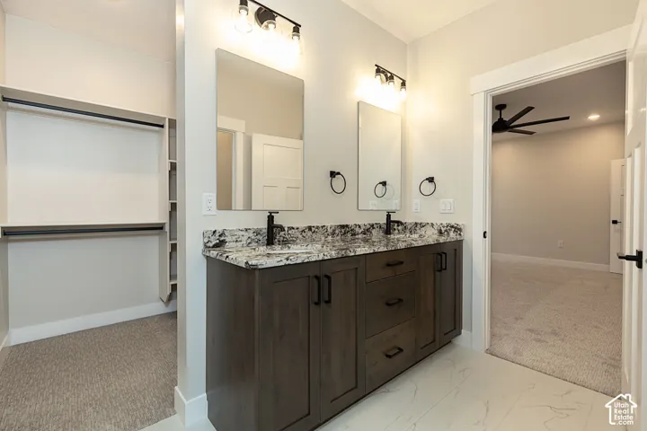 Dual vanity with stone countertop, wood-finish cabinetry, and black fixtures