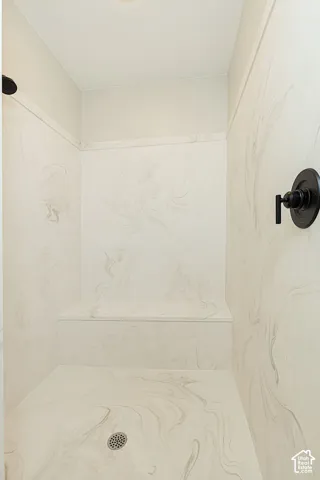 Shower enclosure featuring a built-in bench, matte black shower head, matte black controls, and patterned wall panels