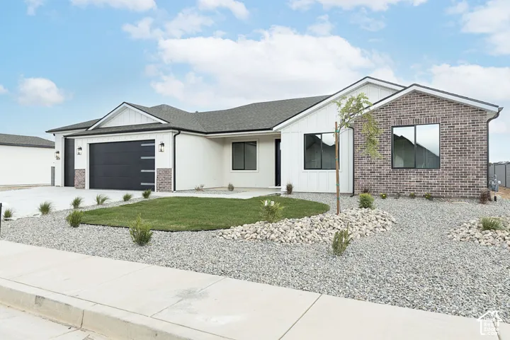 Contemporary facade featuring white siding, brick accents, and a dark asphalt shingle roof