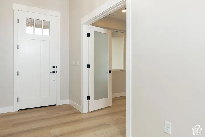 Entry with a four-pane transom door, wood-finish flooring, and crisp white trim