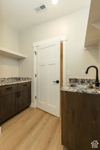 Wood-finish flooring, dark wood cabinetry, light-toned countertops, under-mount sink, and matte black hardware