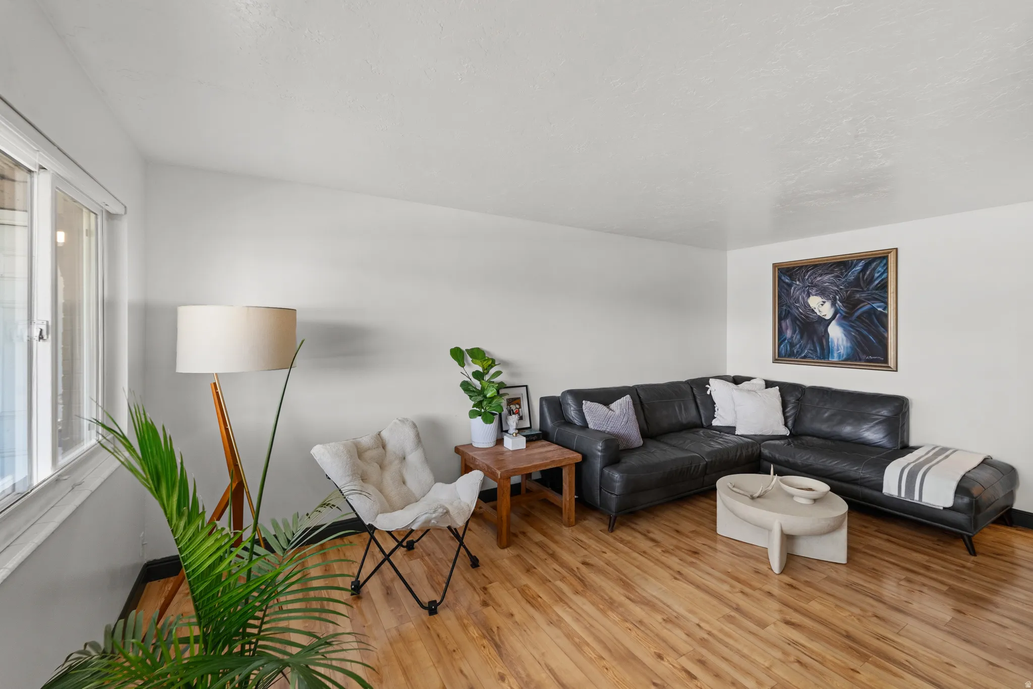 Light wood-finish flooring, white walls, and a large window providing natural light