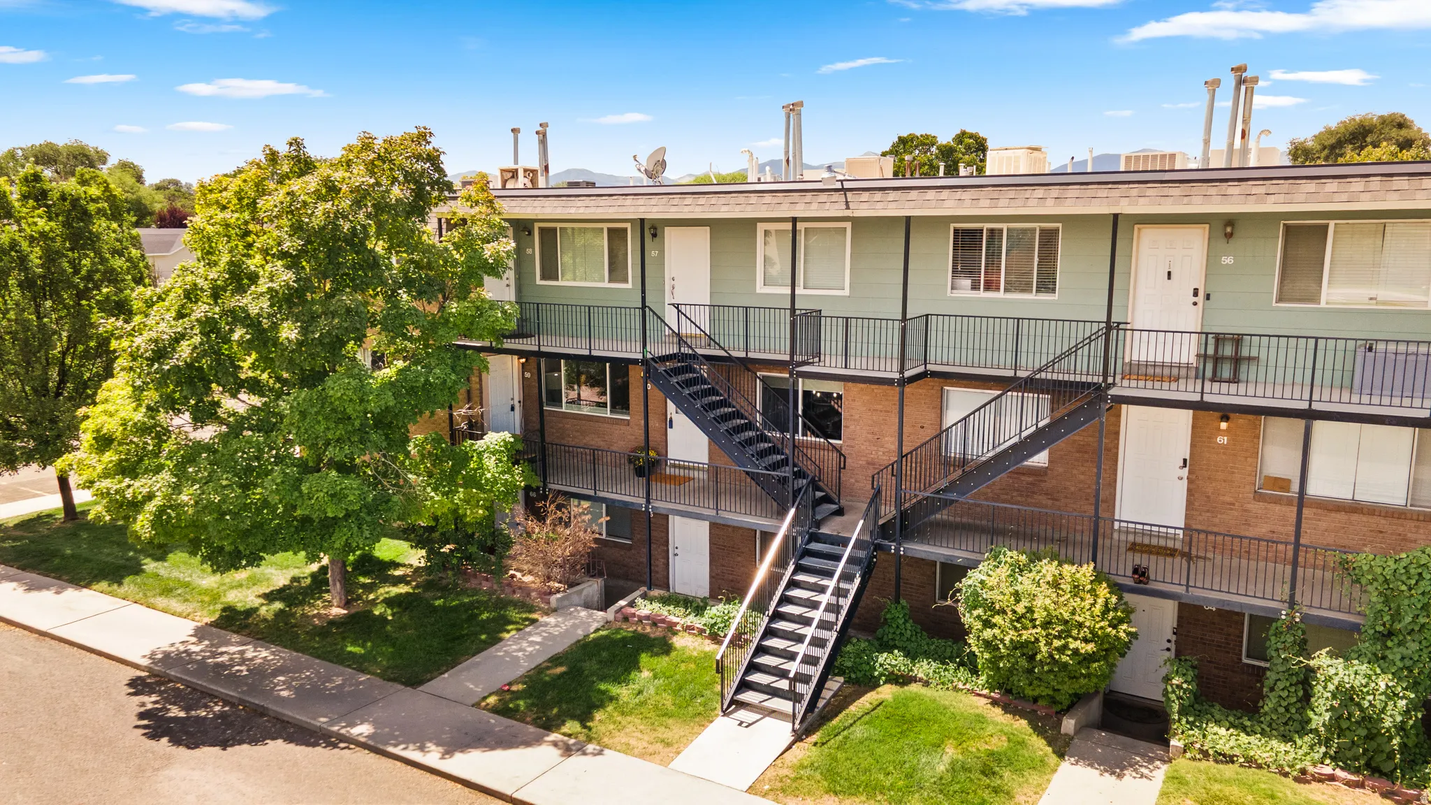 Multi-story building featuring brick and panel siding, multiple exterior entrances, and established landscaping