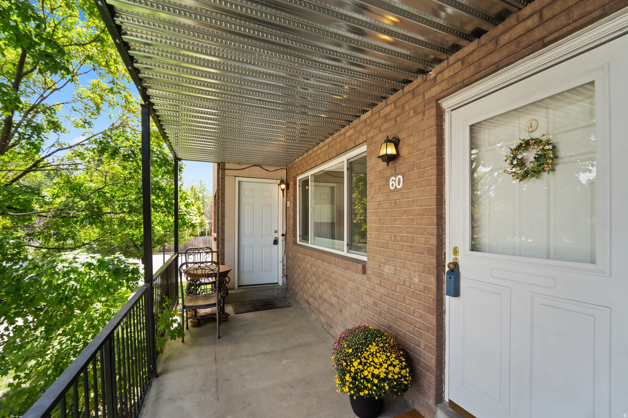 Brick exterior with a covered concrete balcony, black metal railing, and a corrugated metal ceiling