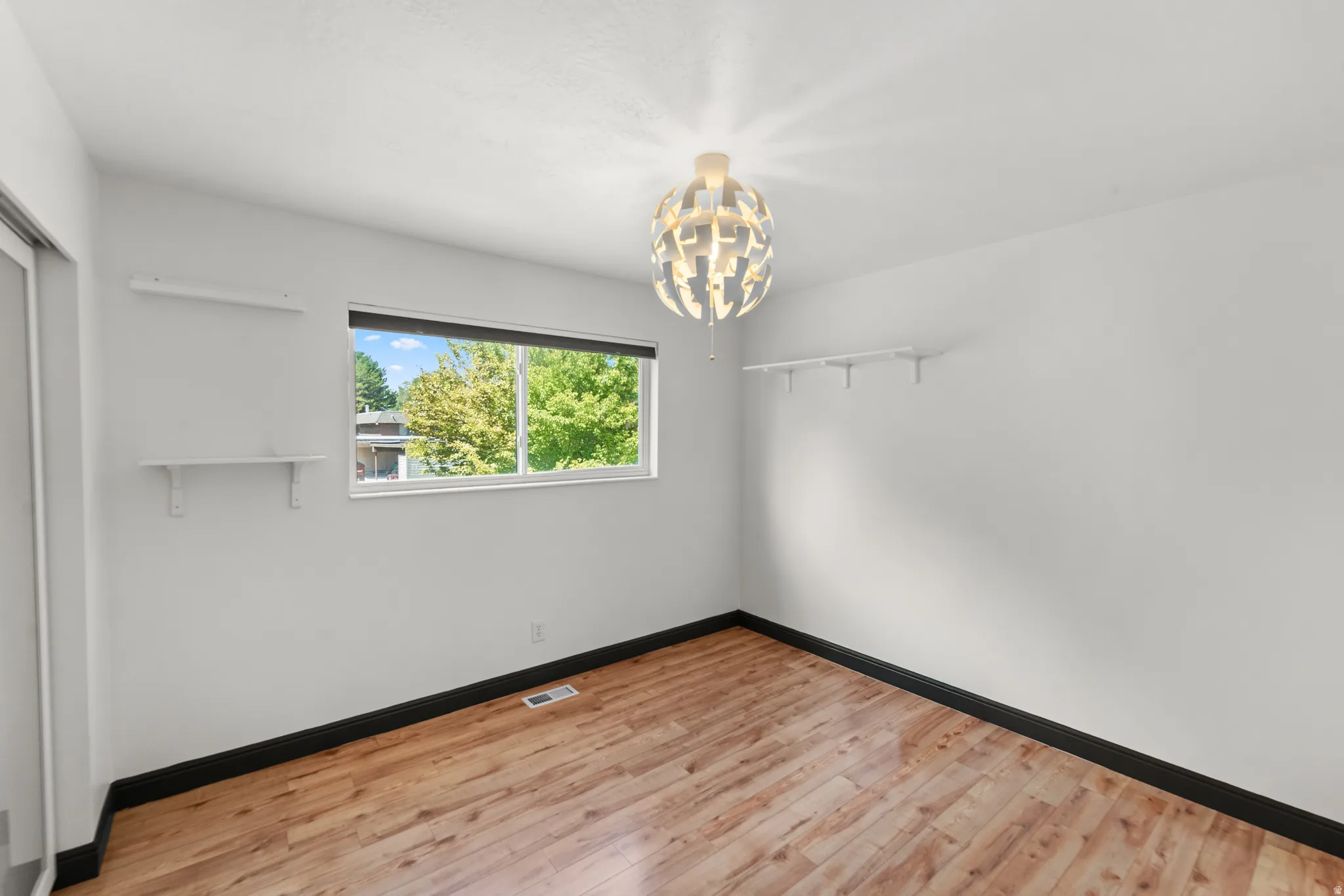 Wood-finish flooring, white walls, and a modern ceiling light fixture