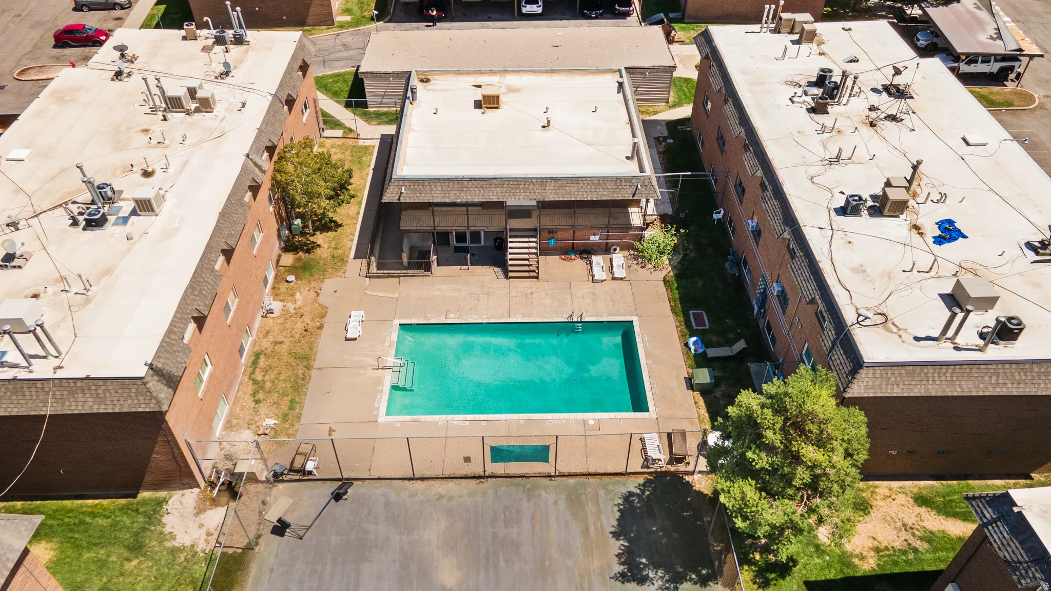 Outdoor swimming pool with surrounding concrete patio and fenced perimeter