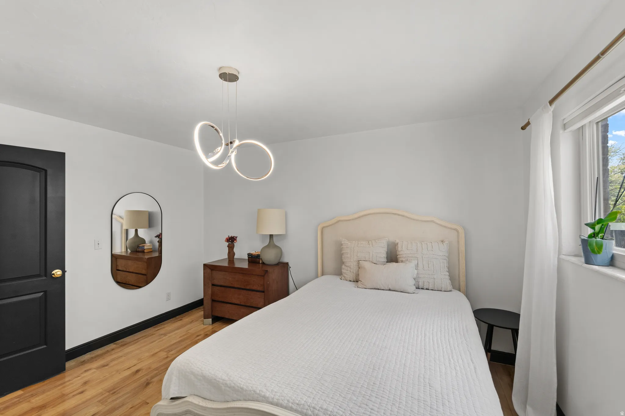 Wood-finish flooring with dark trim, modern ceiling fixture, and a window for natural light