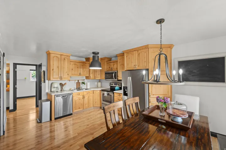Kitchen featuring wood-finish cabinetry, stainless steel appliances, white countertops, and wood-finish flooring