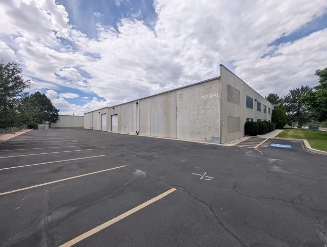 Concrete exterior with multiple service bay doors, dedicated parking lot, and mature perimeter landscaping
