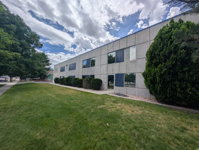 Concrete panel exterior with multiple windows, ground-level shrubbery, and a well-maintained lawn