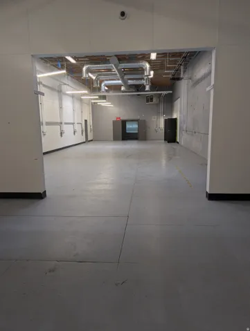 Expansive open space featuring high ceilings, exposed ductwork, concrete flooring, and ample overhead lighting