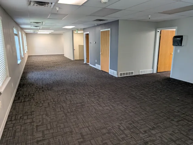 Spacious second floor interior featuring patterned carpet flooring, multiple windows with blinds, and white trim