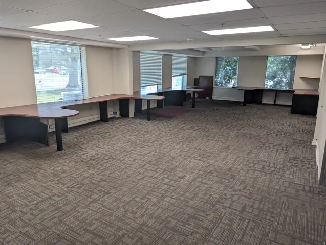 Recessed lighting, large windows with blinds, patterned carpet flooring, built-in desks, and drop ceiling