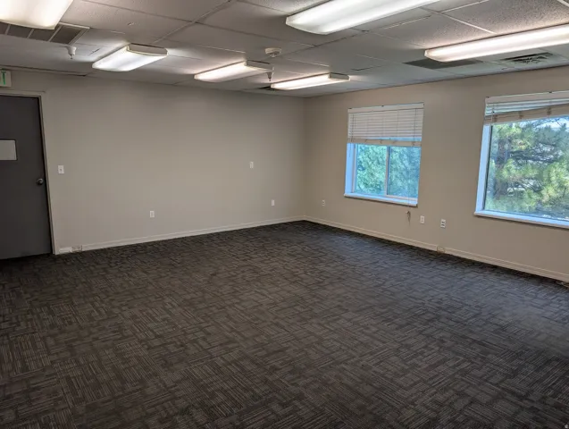 Second Floor. Carpet tile flooring, multiple windows, overhead fluorescent lighting, drop ceiling, and a solid door