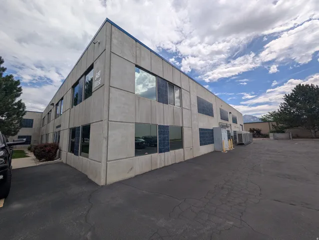 Two-story commercial building featuring multiple windows, a concrete panel exterior, and a paved parking area