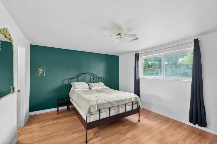 Wood-finish flooring, accent wall, ceiling fan, and window