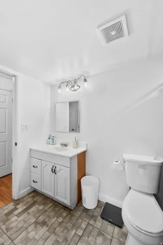White vanity with a single basin sink, wall-mounted mirror, and overhead four-bulb light fixture