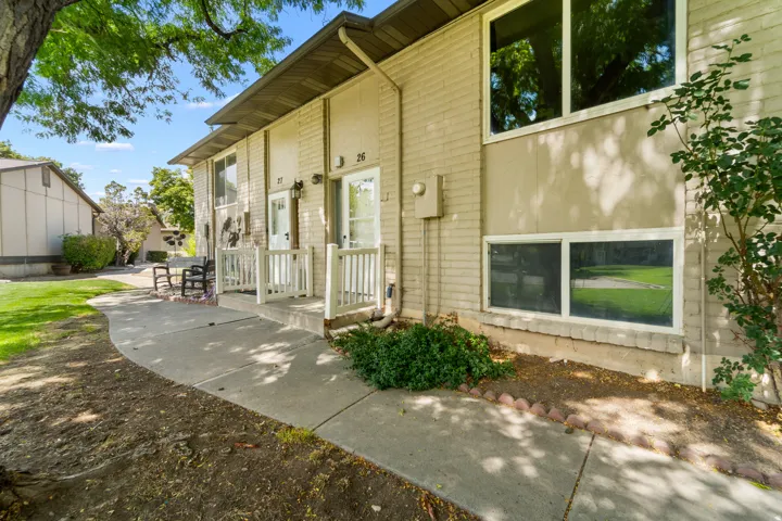 Brick exterior with white window frames and a concrete pathway