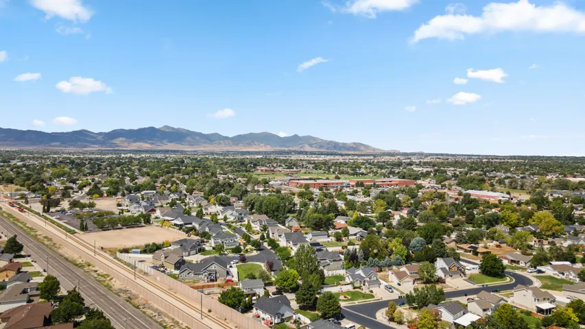 Expansive residential area with numerous homes, mature trees, mountain backdrop, and a distinct railroad line