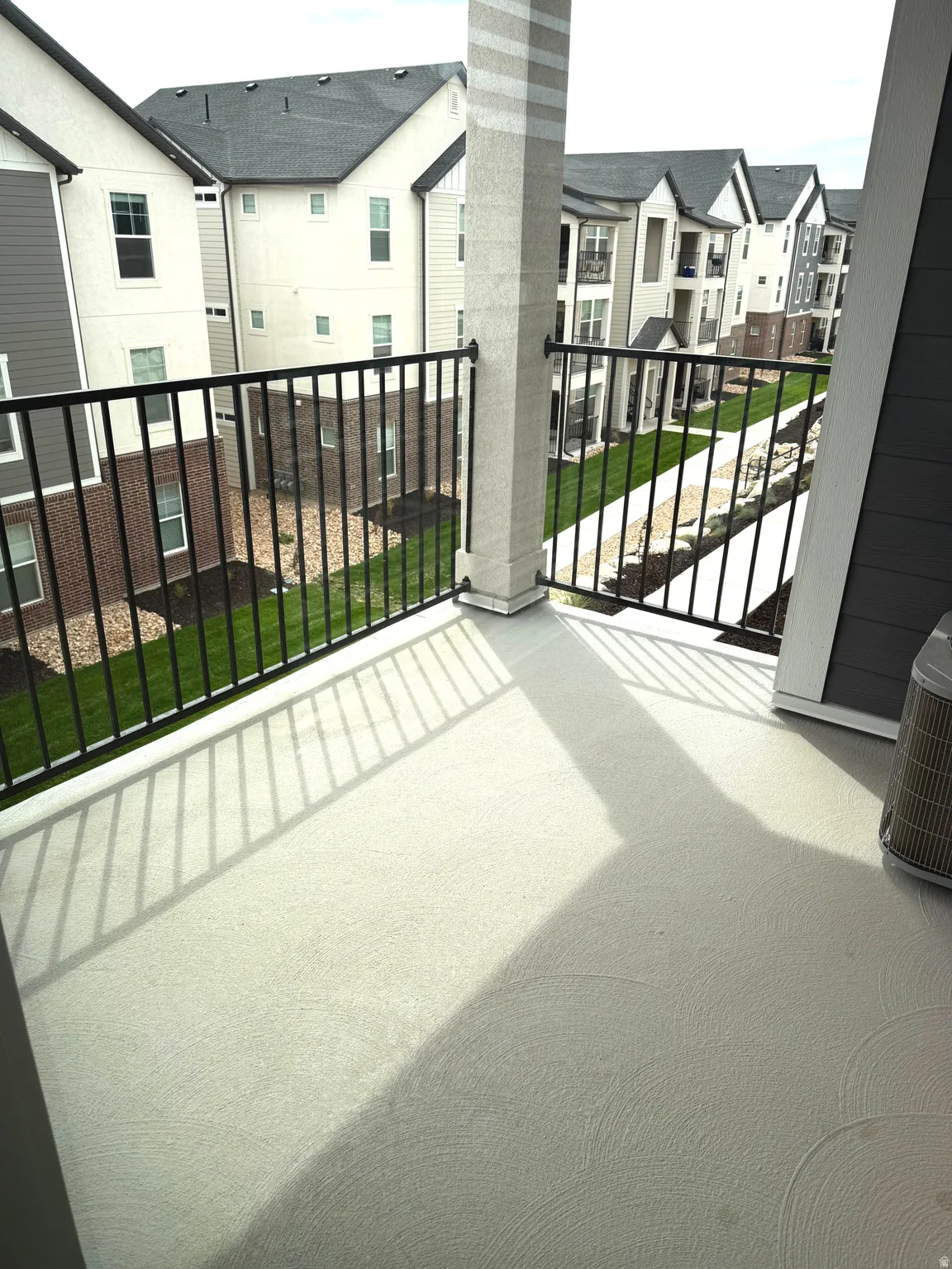 Spacious elevated deck featuring composite decking with linear texture, black aluminum railing with horizontal balusters, and a structural support column