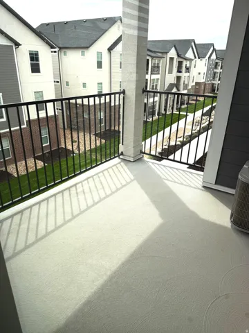 Spacious elevated deck featuring composite decking with linear texture, black aluminum railing with horizontal balusters, and a structural support column
